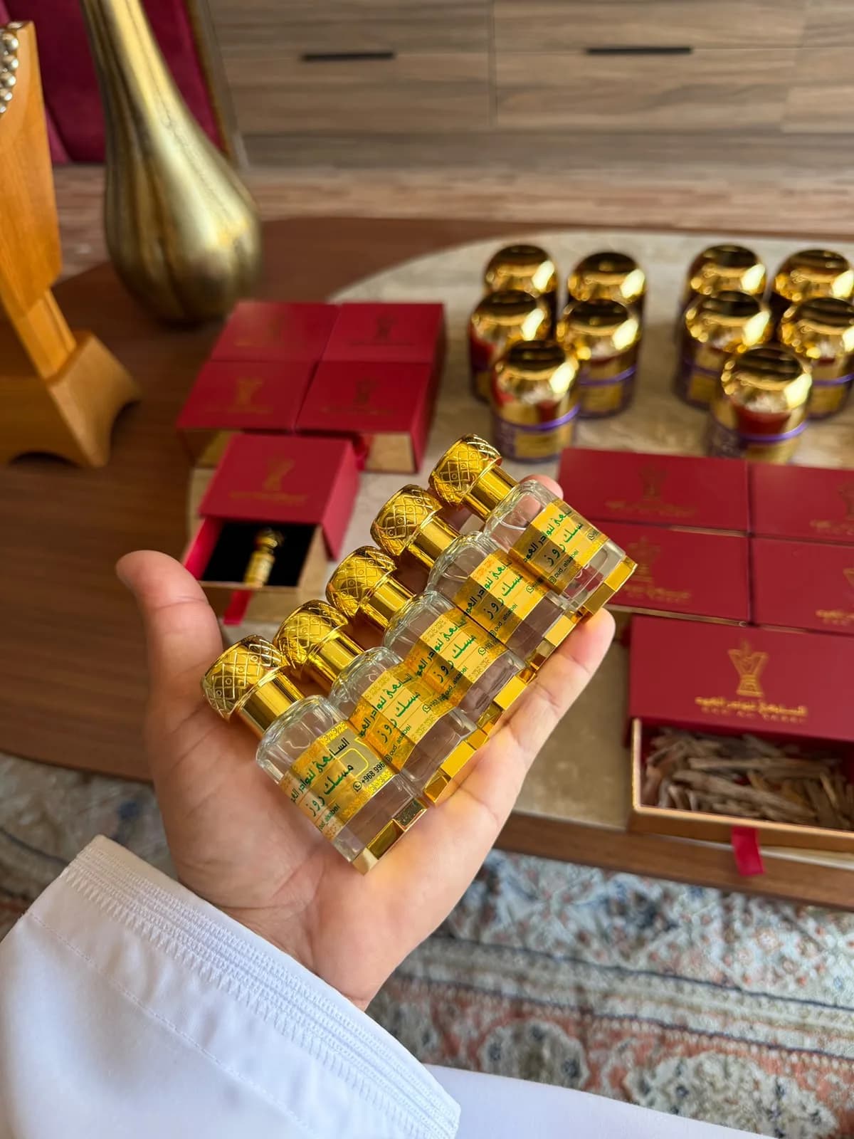 قوارير صغيرة من مسك روز بأغطية ذهبية في راحة اليد