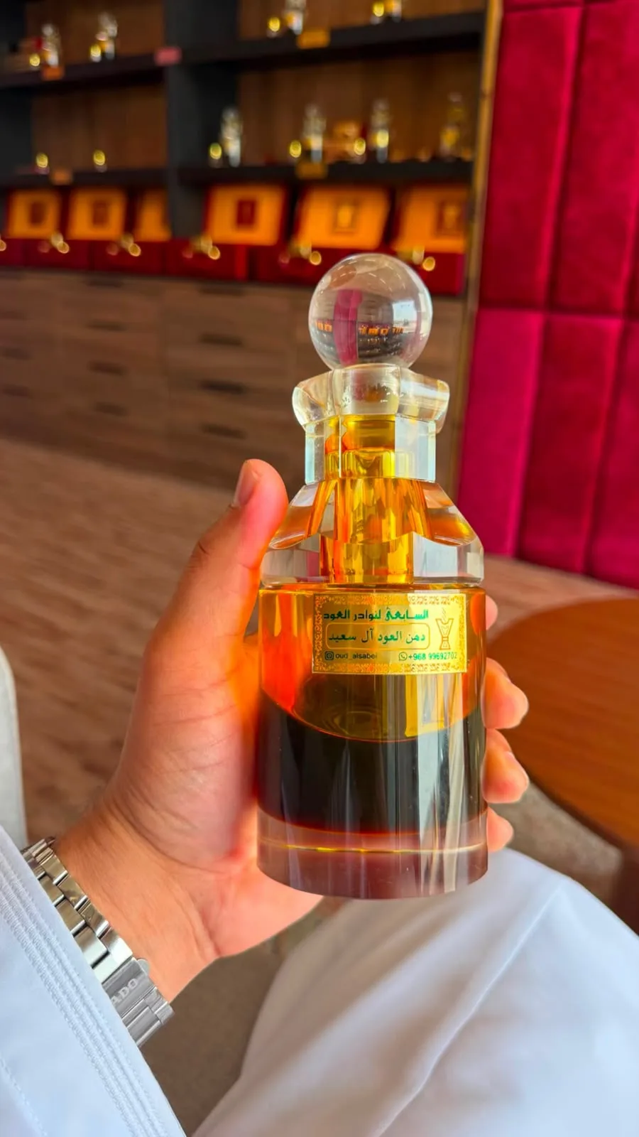 قارورة كريستال من دهن آل سعيد بغطاء كروي أمام رفوف المحل